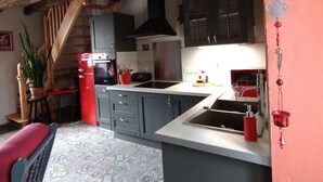 Una cocina con una isla central, armarios oscuros y un refrigerador rojo.