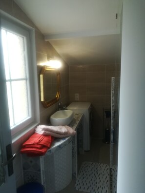 Un baño con ventana, lavabo, espejo y ducha.