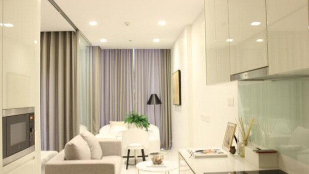 A modern hotel room with a sofa, a small table, a lamp, and a view of the city through large windows. - Ariva Hyde Sukhumvit 11 - Adults Only (Bangkok)