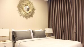 A hotel room with a large bed, two bedside tables with lamps, a wall-mounted mirror, and a curtain on the window. - Ariva Hyde Sukhumvit 11 - Adults Only (Bangkok)