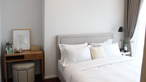A hotel room with a bed, a desk with a chair, a lamp, and a window with curtains. - Ariva Hyde Sukhumvit 11 - Adults Only (Bangkok)