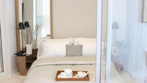 A hotel room with a large bed, a bedside table with a tray of breakfast items, a mirror, and a view of the outdoors. - Ariva Hyde Sukhumvit 11 - Adults Only (Bangkok)