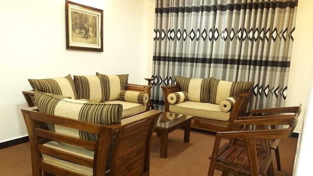 Una sala de estar con un sofá, dos mesitas auxiliares y una silla de madera.