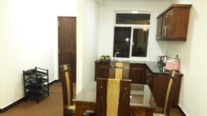 Comedor con mesa de vidrio y sillas de madera, cocina con ventana y una puerta al fondo.