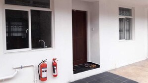 Un edificio blanco con dos ventanas, una puerta y un extintor colgado en la pared.