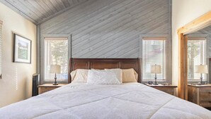 A bedroom with a large bed, wooden headboard, two bedside tables with lamps, and a large mirror on the wall. - MST #1-Large townhome in heart of town. Easily sleeps 10! Beautifully updated (Mammoth Lakes)