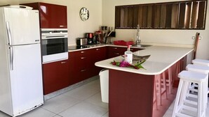 A kitchen with a central island, white refrigerator, and red cabinets.