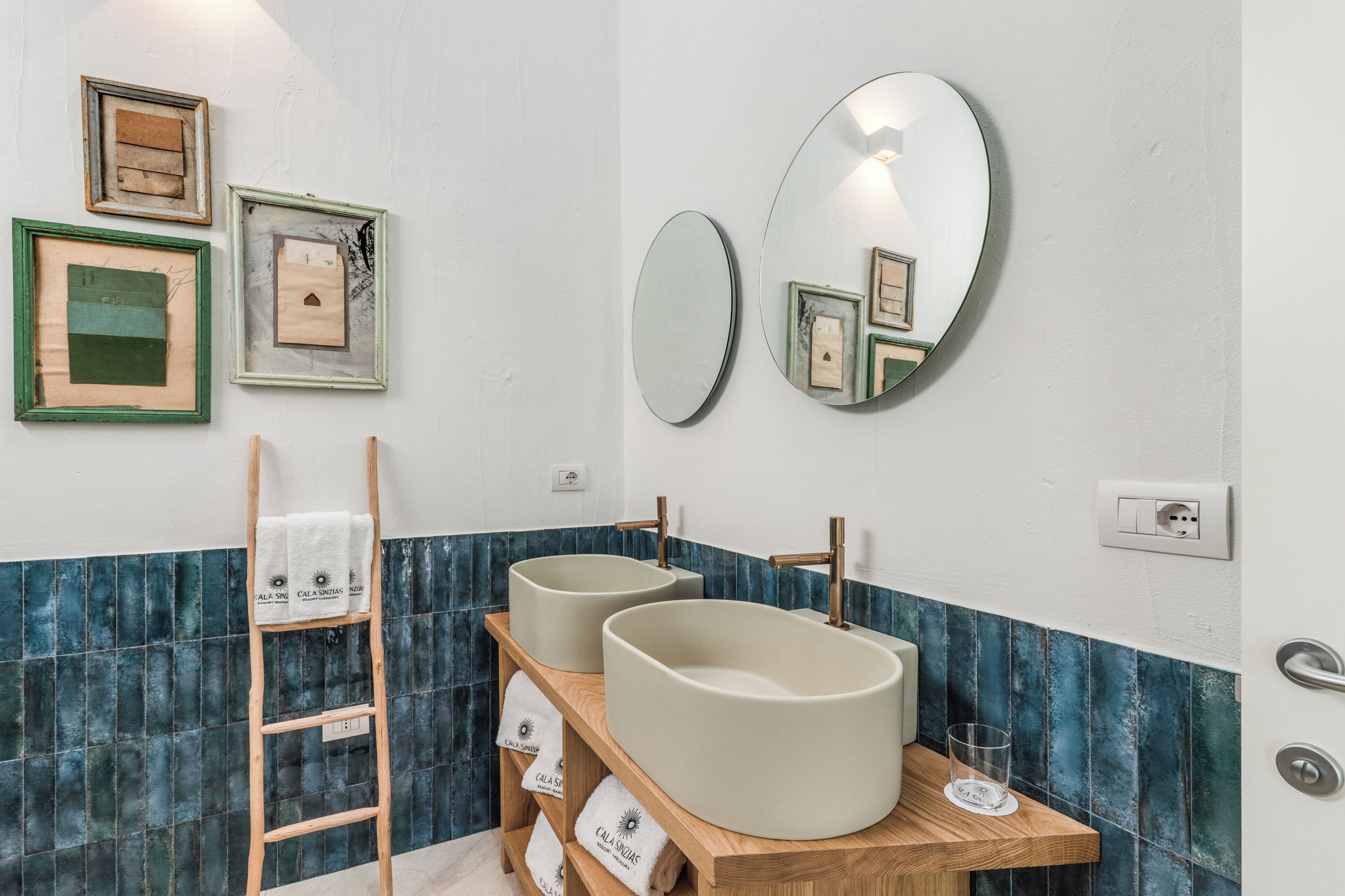 A bathroom with two sinks, a mirror, and framed pictures on the wall.