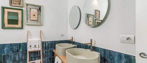 A bathroom with two sinks, a mirror, and framed pictures on the wall.