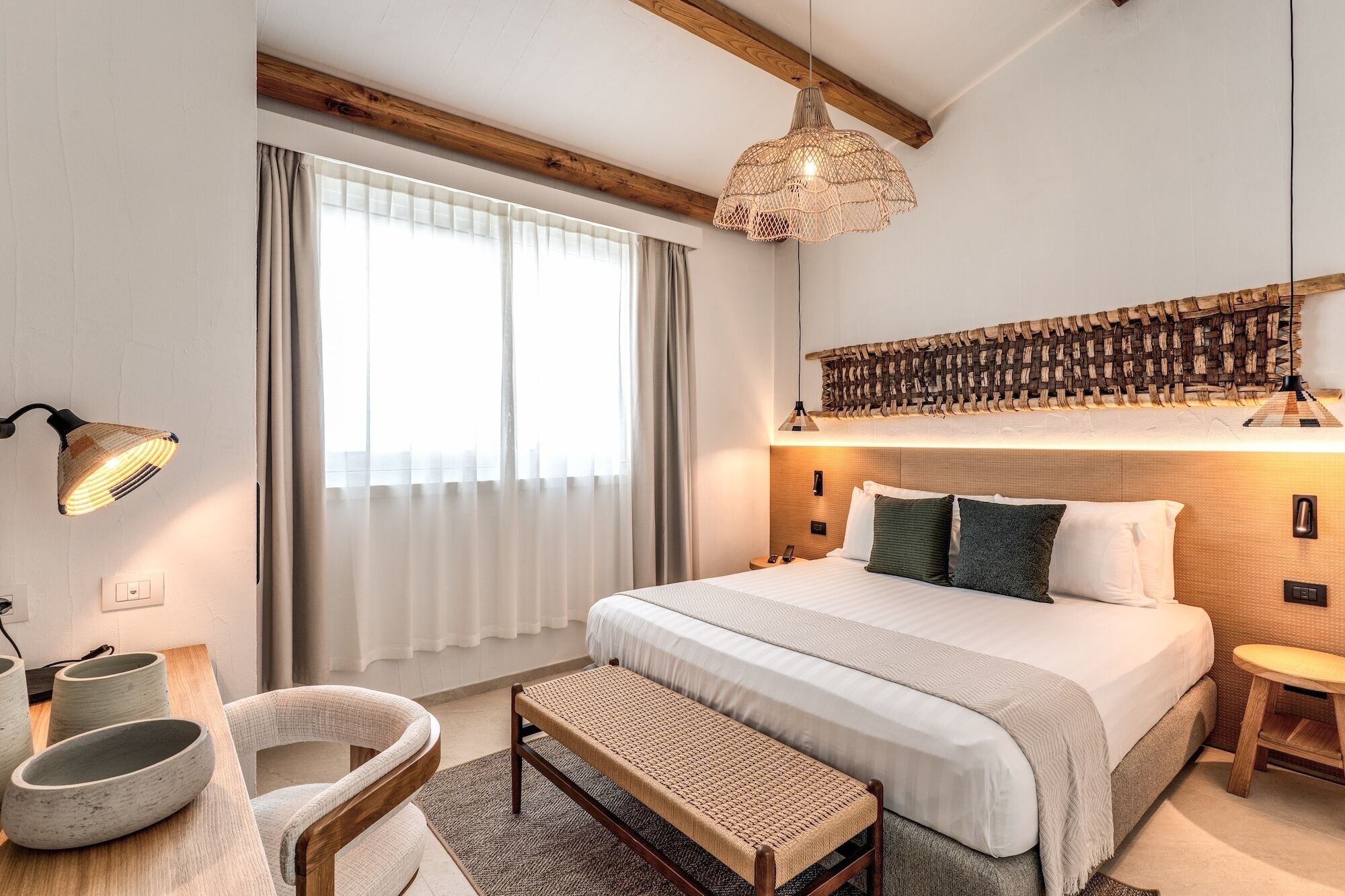 A bedroom with a bed, bedside table, lamp, and a woven headboard.