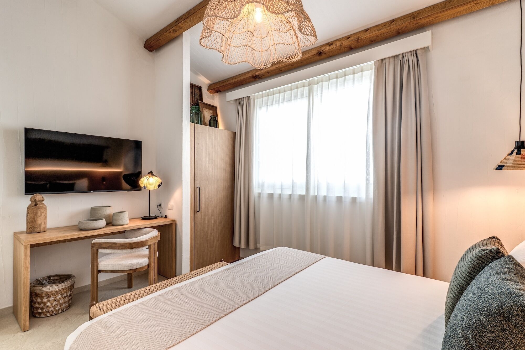 Ein Schlafzimmer mit einem Bett, einem Schreibtisch mit Stuhl, einem Fernseher und einem Fenster mit Vorhängen.