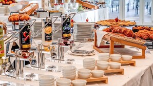 A buffet setup with various food items, including pastries and fruits, arranged on a table with serving dishes and containers. - Cala Sinzias Resort (Castiadas)