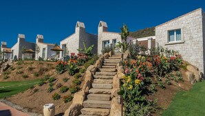 A stone staircase leading to a residential area with stone buildings and a garden with colorful flowers. - Cala Sinzias Resort (Castiadas)