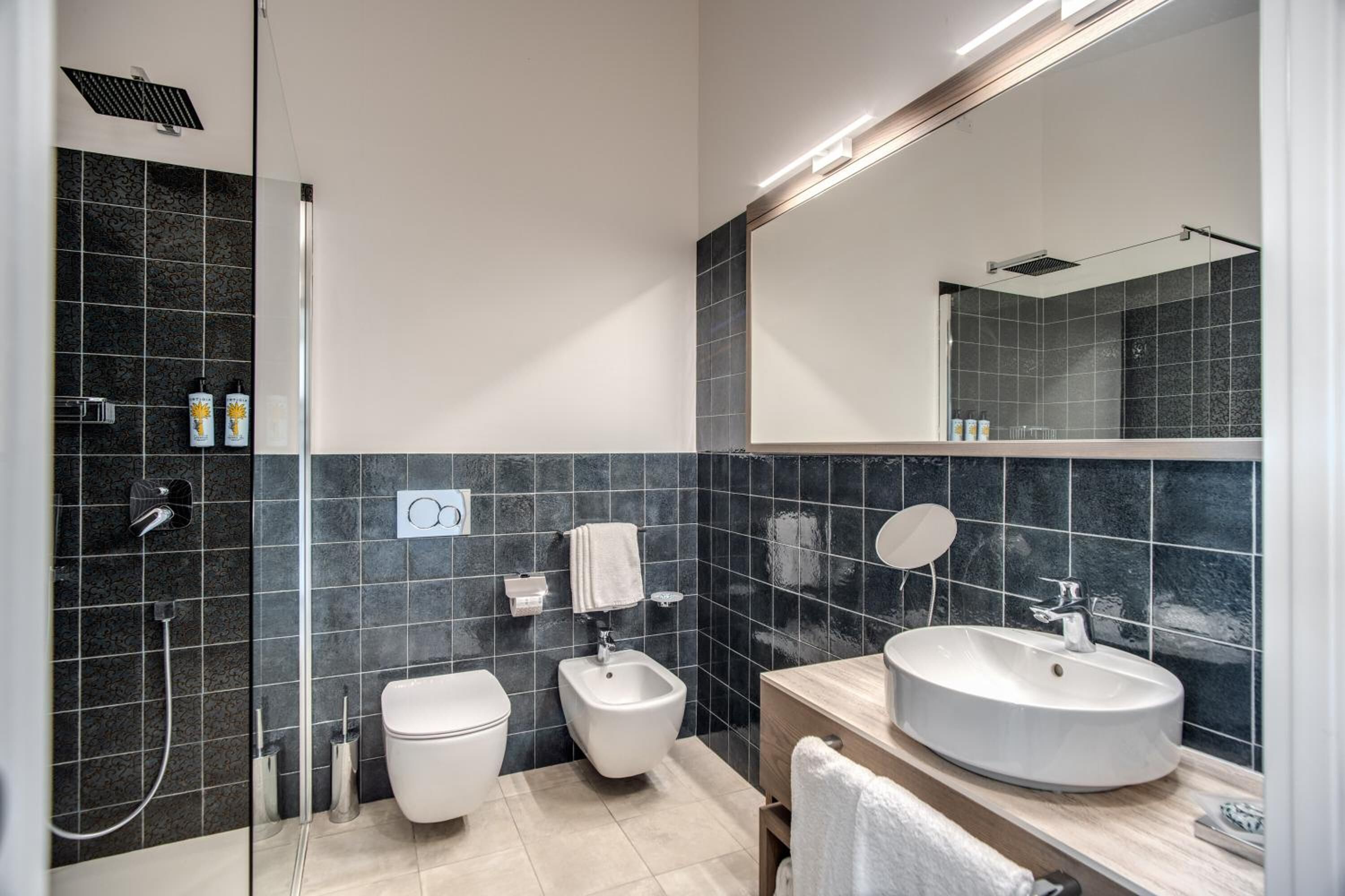 Et moderne badeværelse med bruser, toilet, bidet og vask.