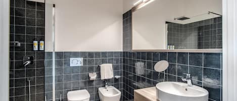 Een moderne badkamer met een douche, toilet, bidet en wastafel.