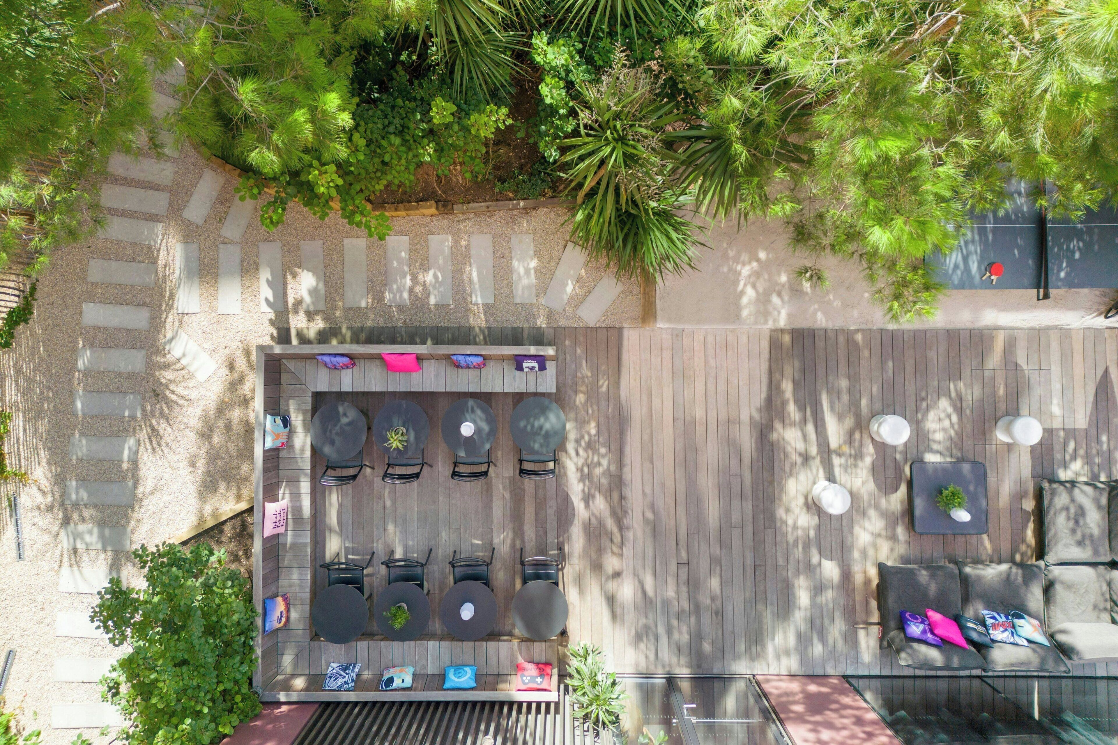 Un patio al aire libre con una terraza de madera, varias zonas de estar y un pequeño jardín.