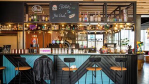Een bar met krukken, een neonreclame en een menubord.