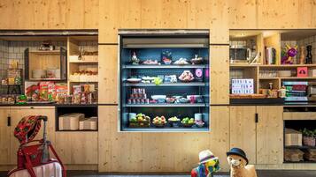 A bakery display with various baked goods and a small stuffed animal wearing a hat.