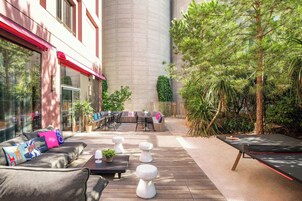 Un patio exterior con zona de estar, mesas y una mesa de ping pong.