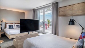 Een moderne hotelkamer met een groot bed, een televisie, een bureau en stadszicht door grote ramen.