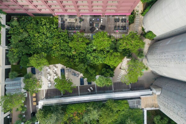 An aerial view of a hotel courtyard with outdoor seating, greenery, and a modern building structure. - Moxy Bordeaux Hotel (Bordeaux)