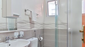 A modern bathroom with a glass-enclosed shower, a sink, and a toilet. - Garni Hotel Koral (Budva)