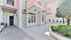 A building with a reception area, stone facade, and potted plants. - Garni Hotel Koral (Budva)