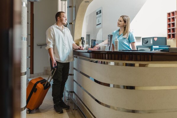 A hotel reception area with a curved counter, a reception desk, and a visible staircase.
