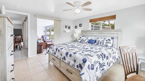 Une chambre à coucher avec un lit, un ventilateur de plafond, une fenêtre donnant sur un beau paysage et une porte menant à un balcon.