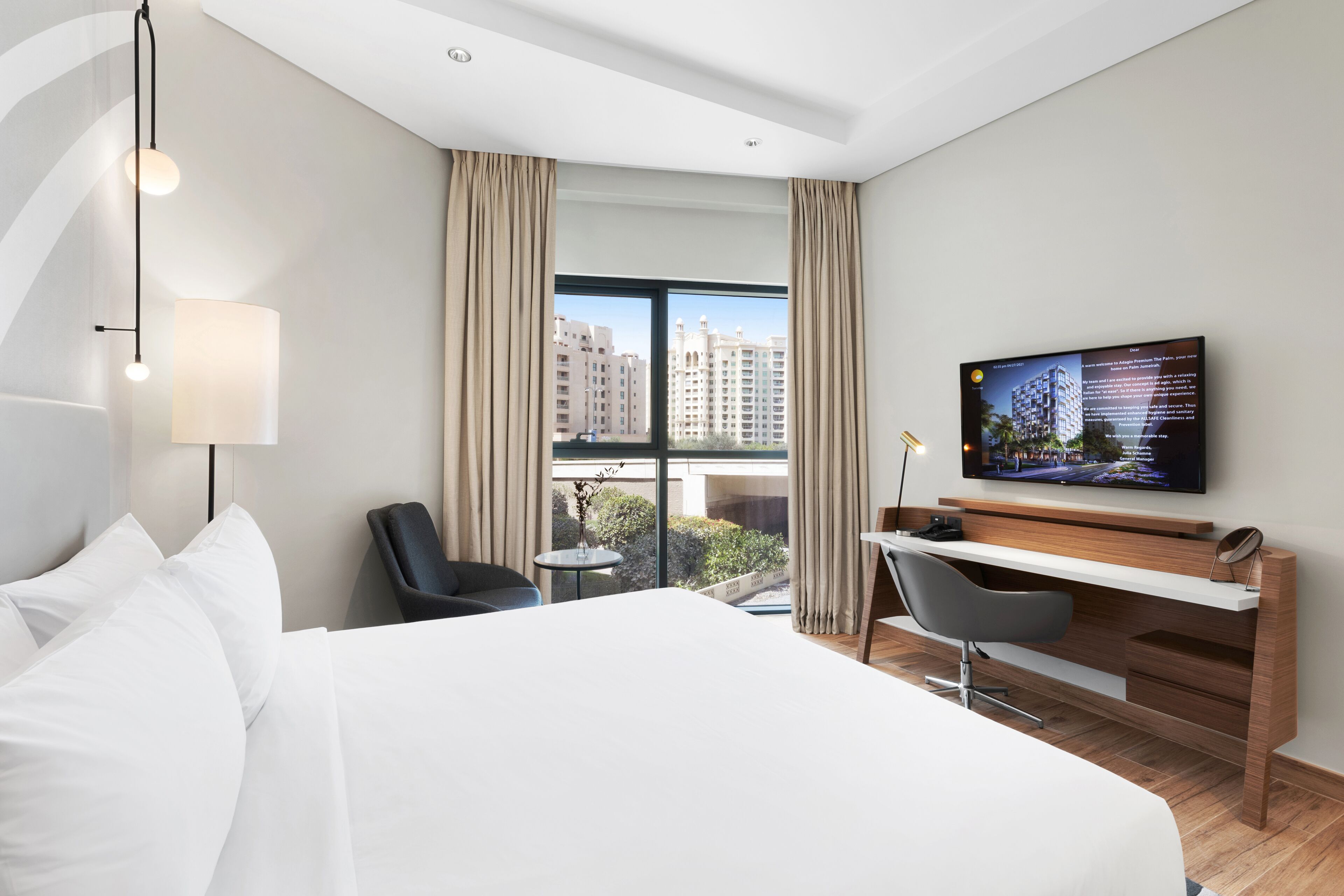Hotelkamer met een groot bed, een bureau, een stoel, een televisie en uitzicht op gebouwen.