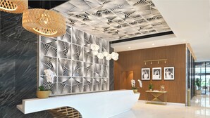 Un área de recepción moderna con un mostrador blanco, pared con patrón geométrico y techo de diseño único.