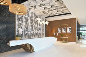 Un área de recepción moderna con un mostrador blanco, pared con patrón geométrico y techo de diseño único.