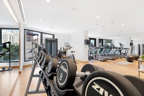 Un gimnasio moderno con varios equipos de ejercicio, incluyendo cintas de correr y mancuernas.