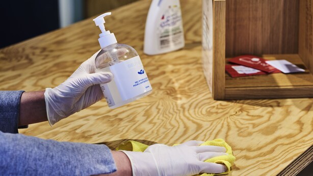 A person cleaning a wooden surface with a yellow cloth and a bottle of cleaning solution. - ibis London Sutton Point (Sutton)