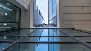 Un edificio moderno con piso de vidrio y superficies reflectantes, creando un efecto espejo.
