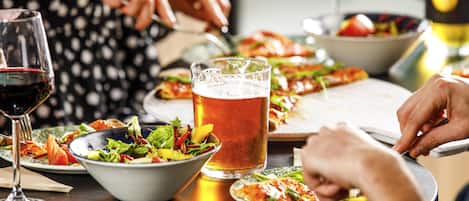A dining table with various dishes, a glass of beer, and a wine glass.