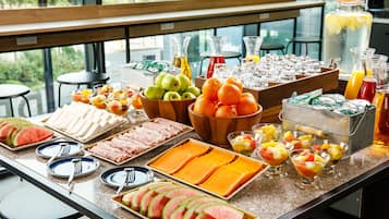 A breakfast buffet with various fruits, cheeses, and beverages.