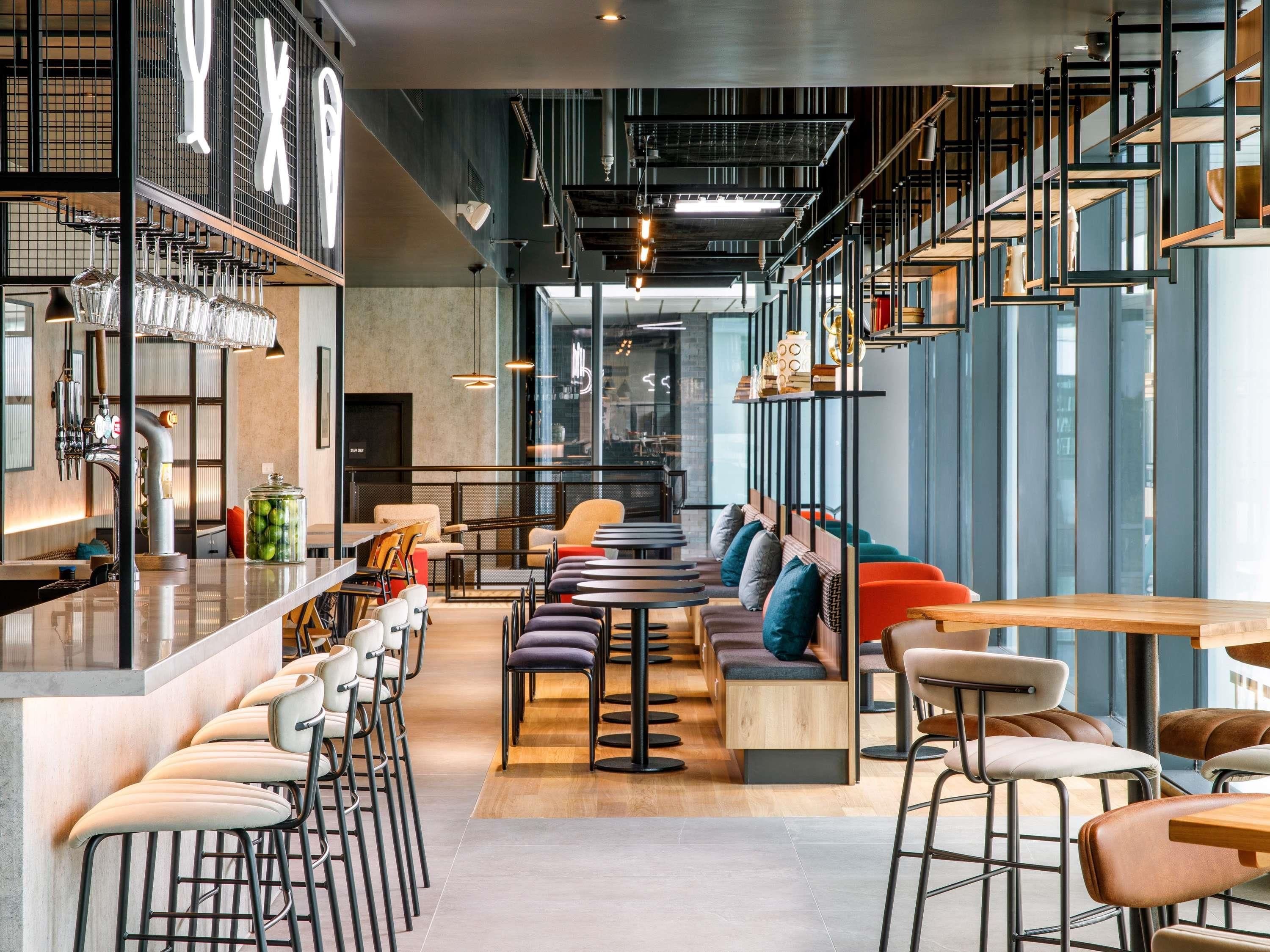 Un moderno bar con taburetes altos, una barra y una zona de estar con bancos acolchados.