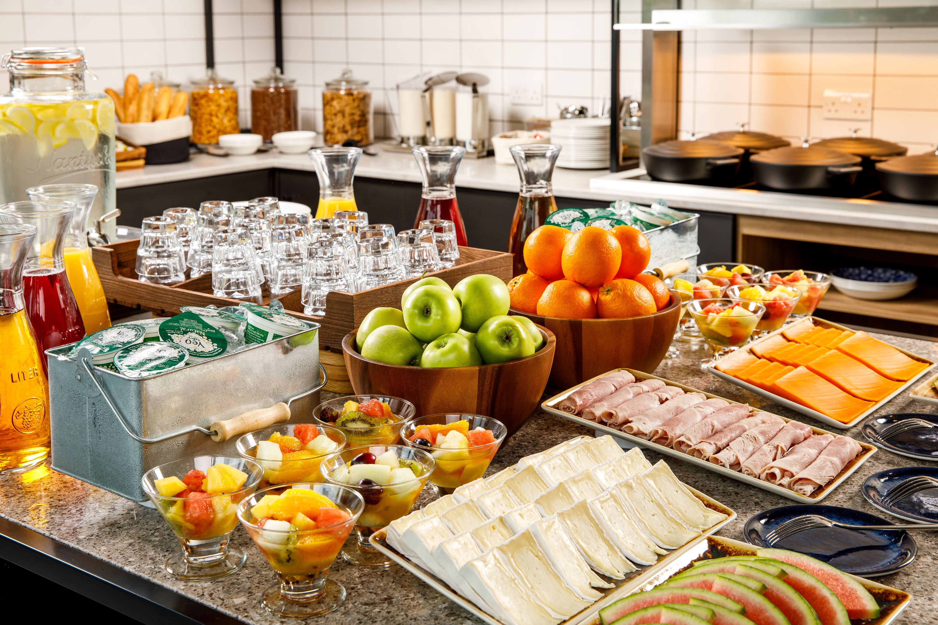 A buffet with various food items including fruits, cheeses, and meats.
