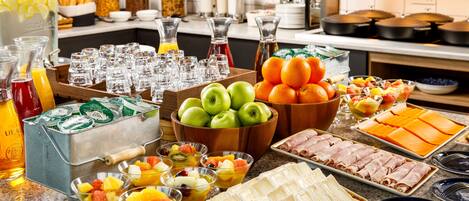 A buffet with various food items including fruits, cheeses, and meats.