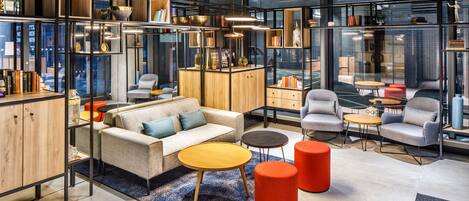 A modern office space with a sofa, chairs, tables, and bookshelves.