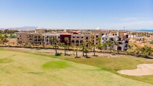 Un resort con varias edificaciones, un amplio espacio cubierto de césped y vistas al mar.