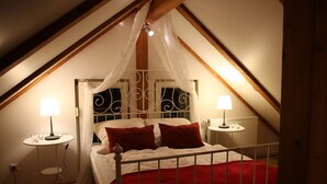 Un dormitorio con cama a dosel, dos mesitas de noche y una mesa redonda con lámpara.