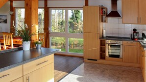 Una cocina moderna con armarios de madera, un ventanal grande y un horno empotrado.
