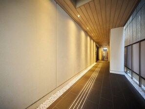 Een gang met een houten plafond, witte muren en een betegelde vloer met een kiezelrand.