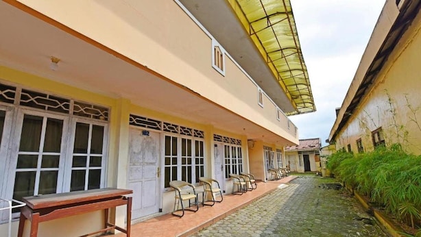 Un edificio con un pórtico, varias puertas y un banco.