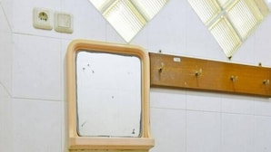 Un baño con lavamanos, espejo y paredes de azulejos.