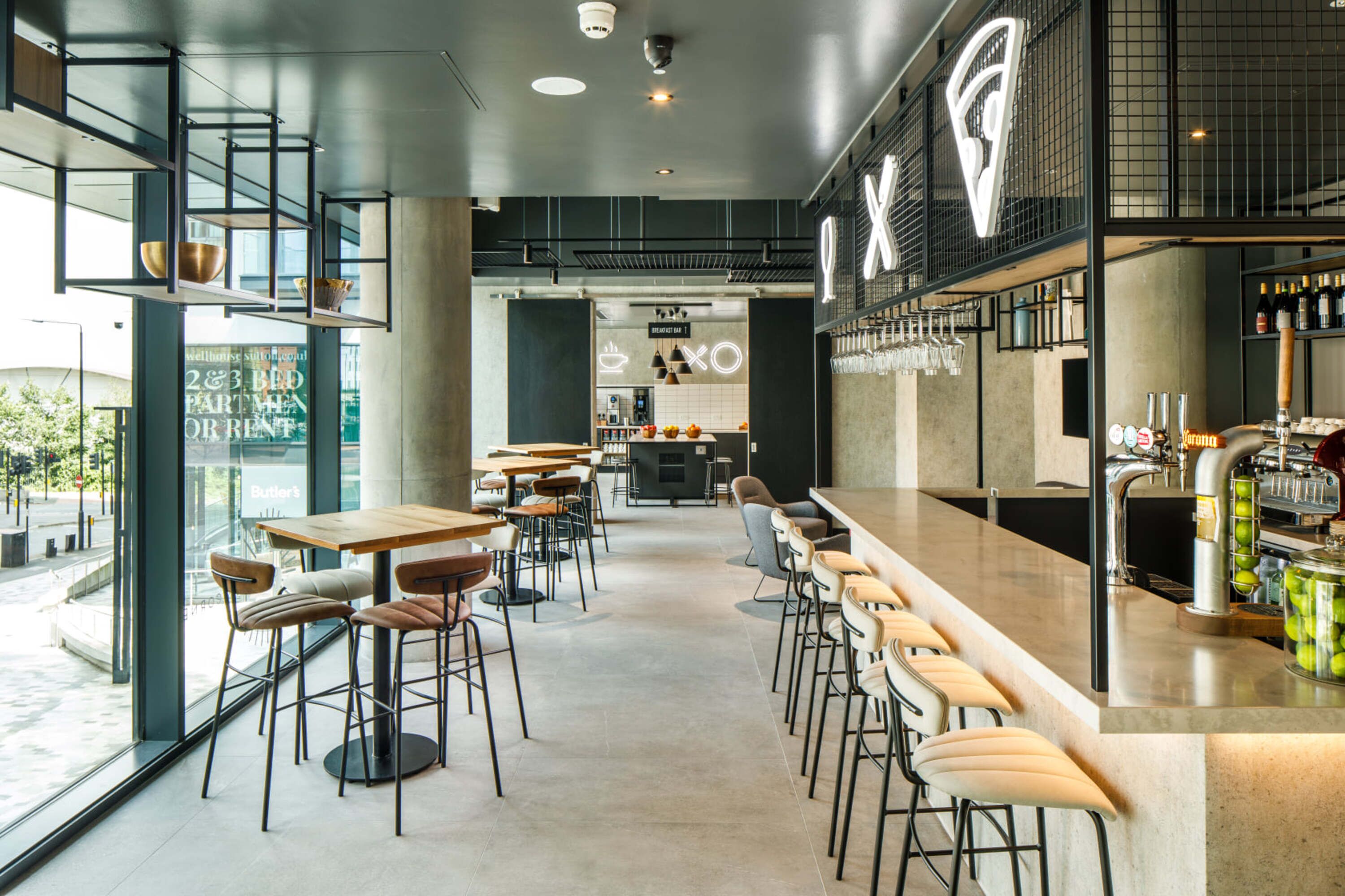 A modern bar area with a long counter, bar stools, and a visible bar stocked with bottles.