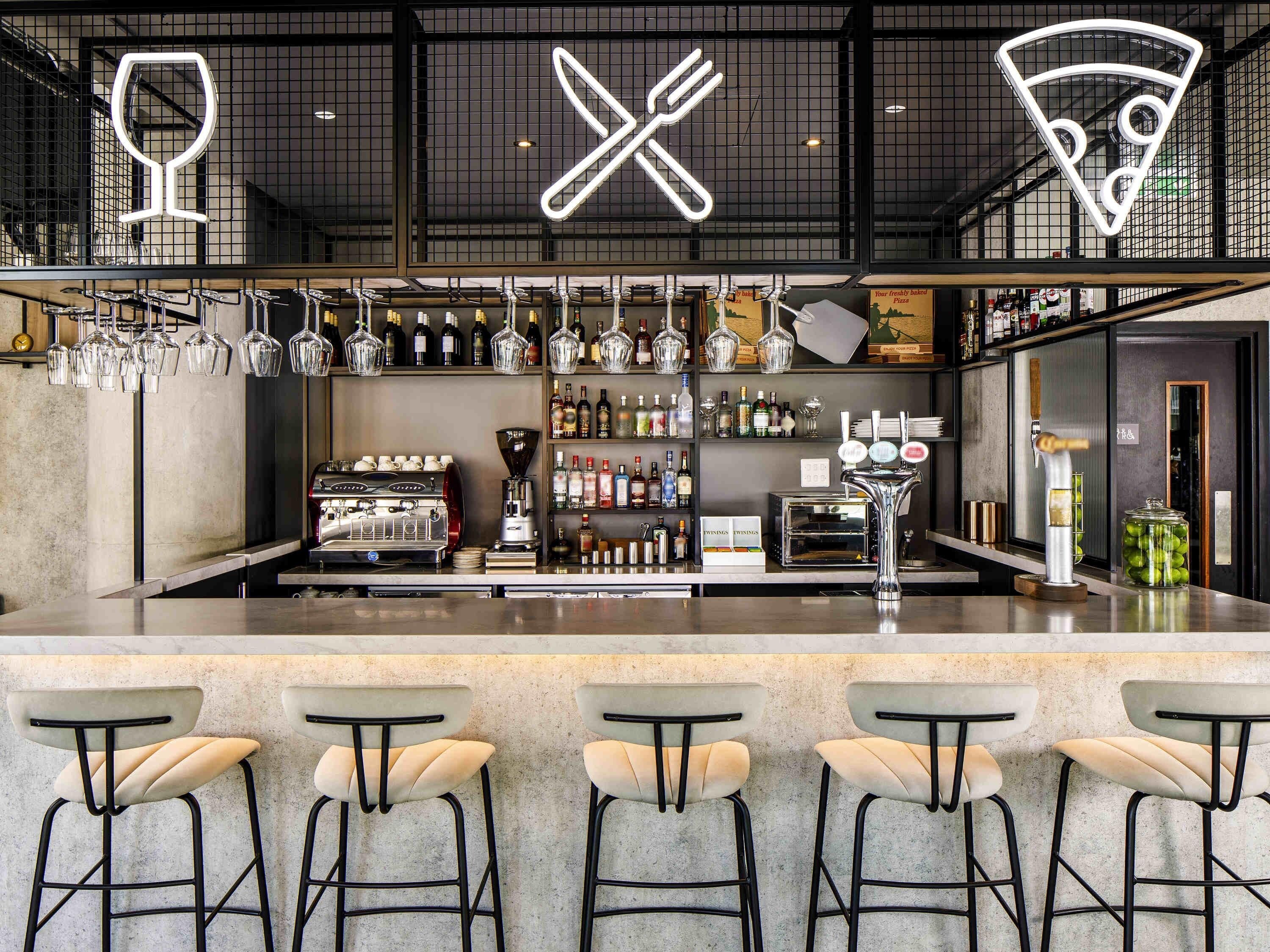 A bar area with a counter, stools, and a variety of bottles and glasses.