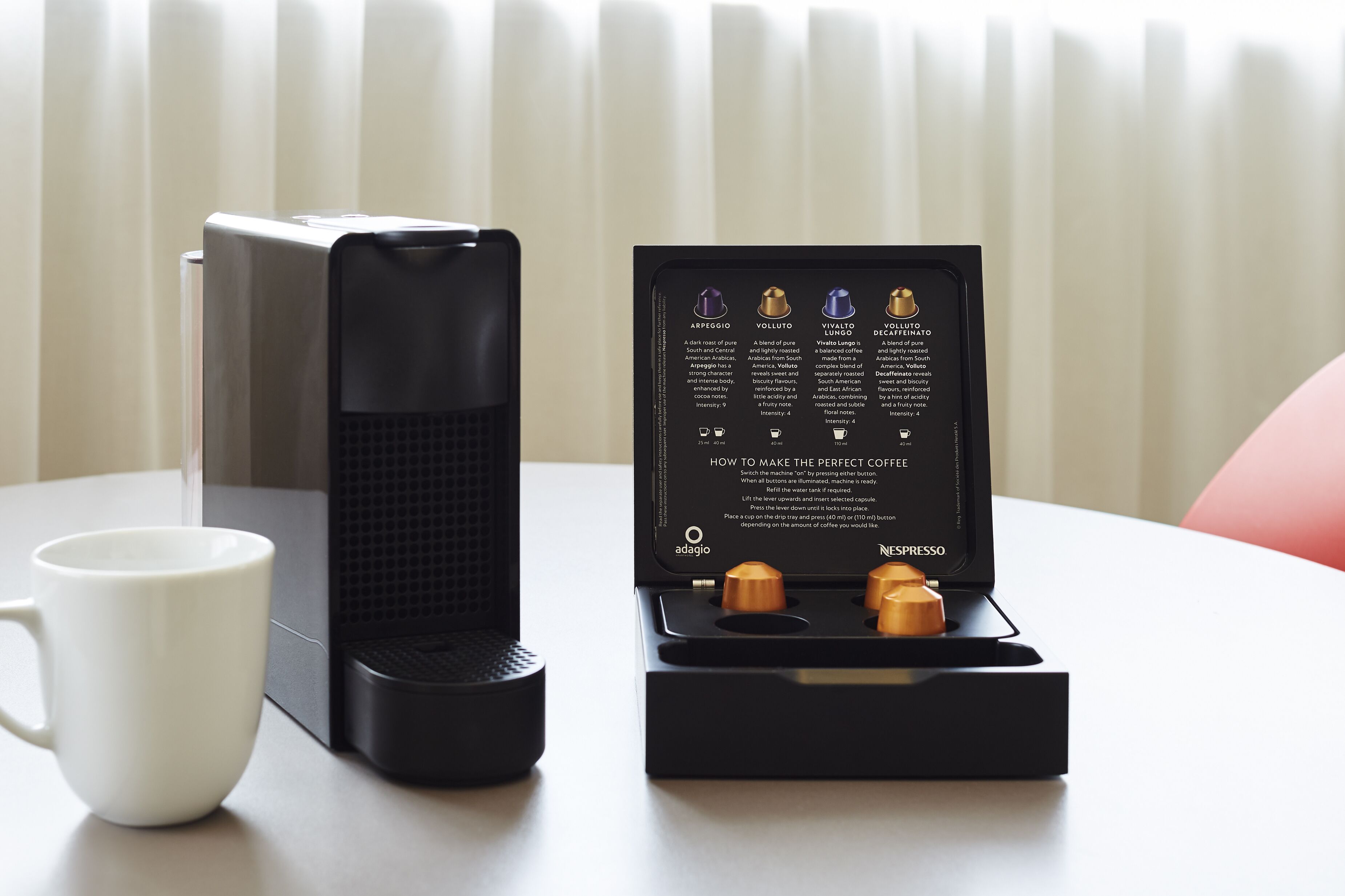 A coffee maker and a coffee pod holder with instructions on a table.
